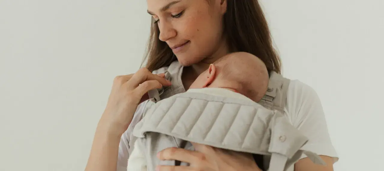 Mutter hält ihr Neugeborenes in einer Trage. Die warme Kleidung neugeborene winter schützt das Baby vor Kälte.