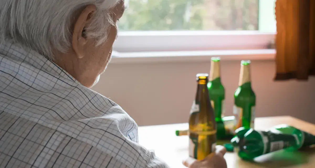 Starszy mężczyzna z butelkami piwa. Alkoholizm po 70. to trudna walka.