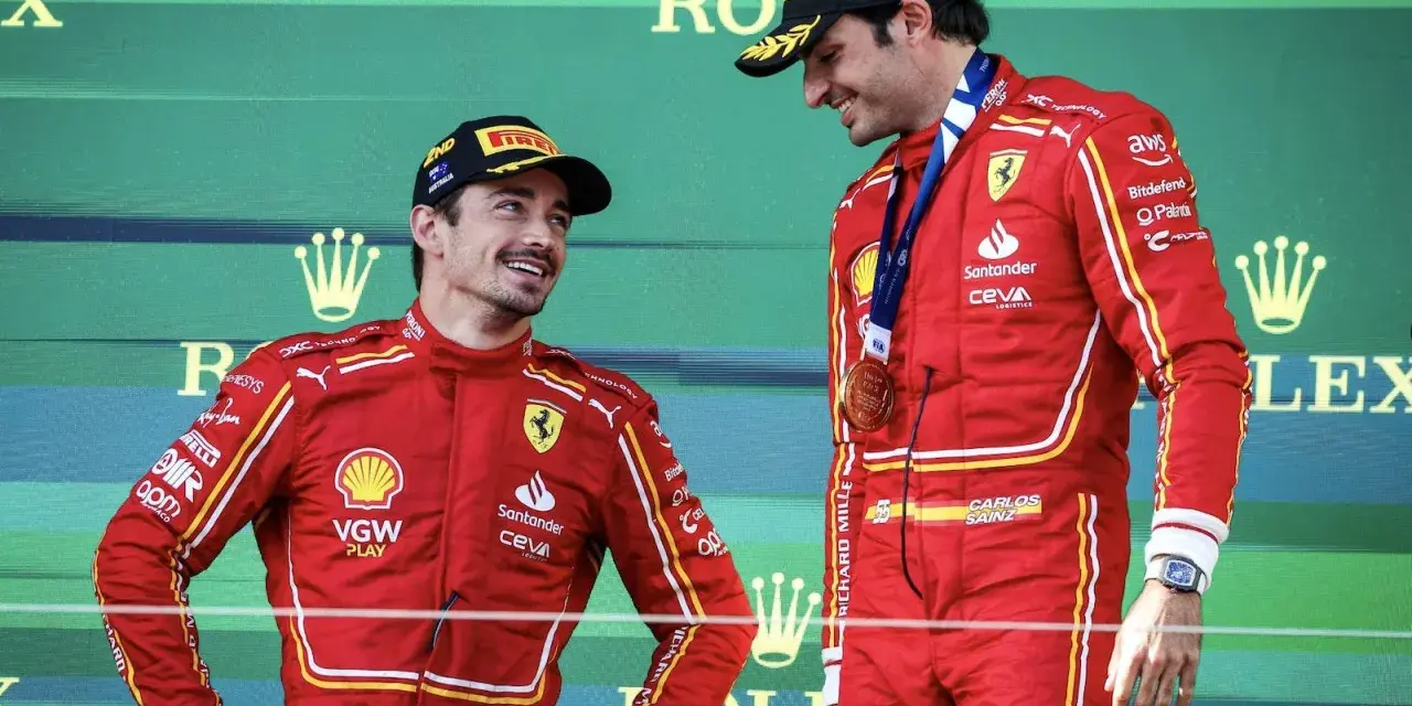 Carlos Sainz, con su altura destacada, sonríe en el podio junto a su compañero.