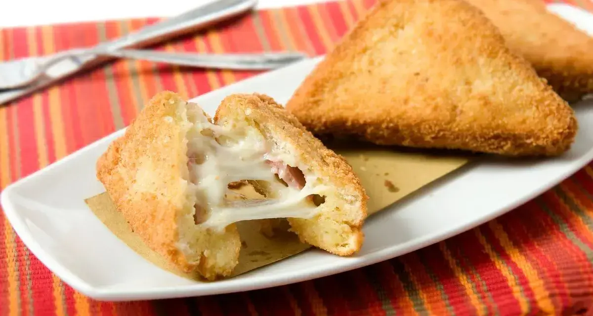 Mozzarella in carrozza dorata e filante, cotta in friggitrice ad aria, servita su un piatto bianco con tovaglietta colorata.