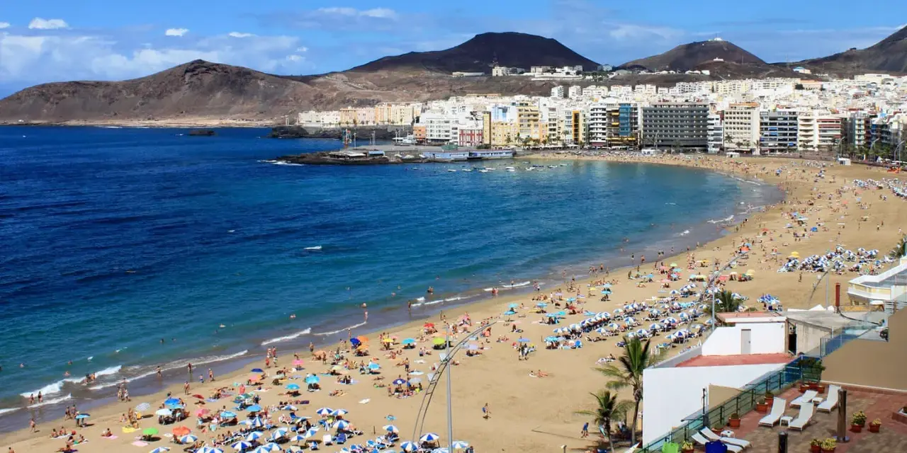 Słoneczna plaża Las Canteras na Gran Canarii, z turystami cieszącymi się ciepłą wodą. Idealna temperatura wody na Gran Canarii zachęca do kąpieli.