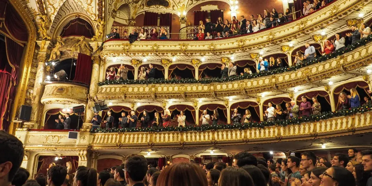 Ein prunkvolles Theater mit vielen Rängen, auf denen Zuschauer sitzen und applaudieren. Hier wird gerade gefragt: was ist eine Operette?