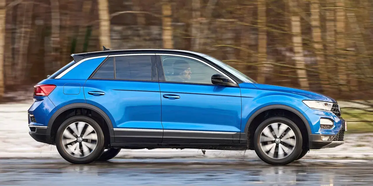 Blauer VW T-Roc fährt durch verschneite Landschaft. Keine Rede von vw t-roc kinderkrankheiten, nur Fahrspaß!