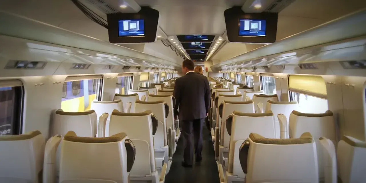 Wnętrze pociągu Pendolino. Para pasażerów idzie przez pusty wagon w drodze z Rzeszowa do Gdańska.