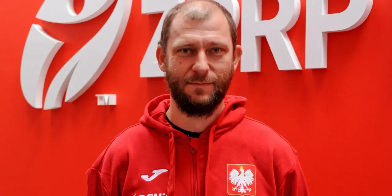 Marcin Wichary, w czerwonej bluzie z orłem, przed logo ZRP.