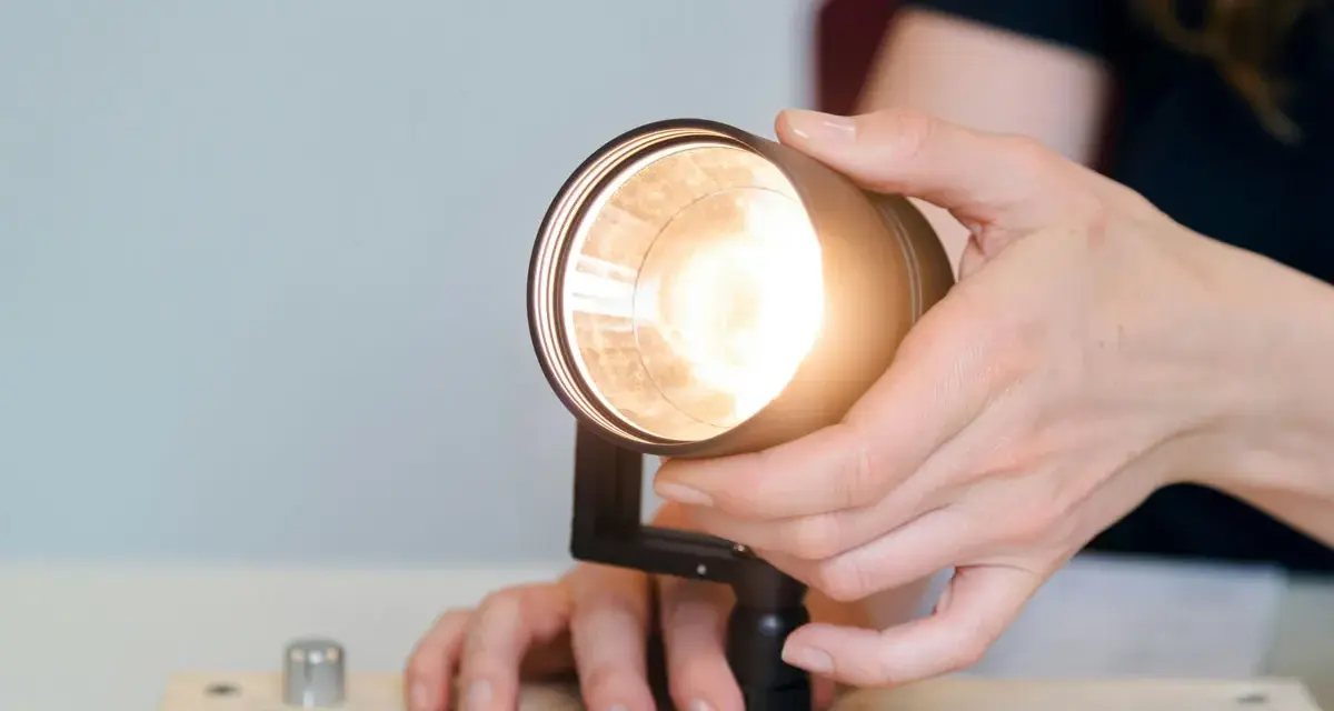 Händer justerar en lampa, kanske för att ta bort dimmer. Ljuset är starkt.