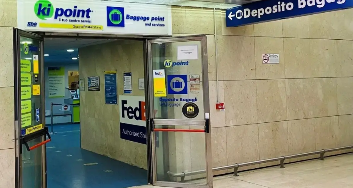 Entrance to a Ki Point baggage storage facility with signage for "Deposito Bagagli" and FedEx.