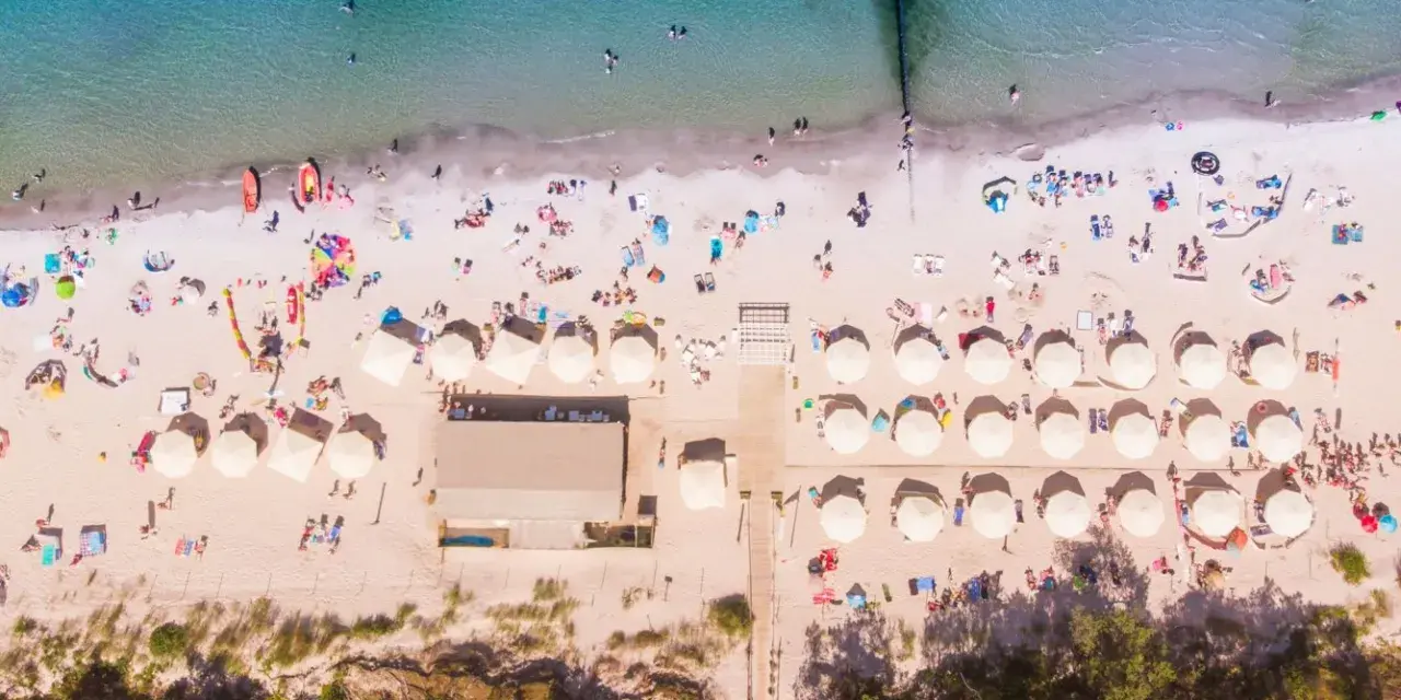Plaża z parasolami i ludźmi, idealna na wakacje all inclusive Polska.
