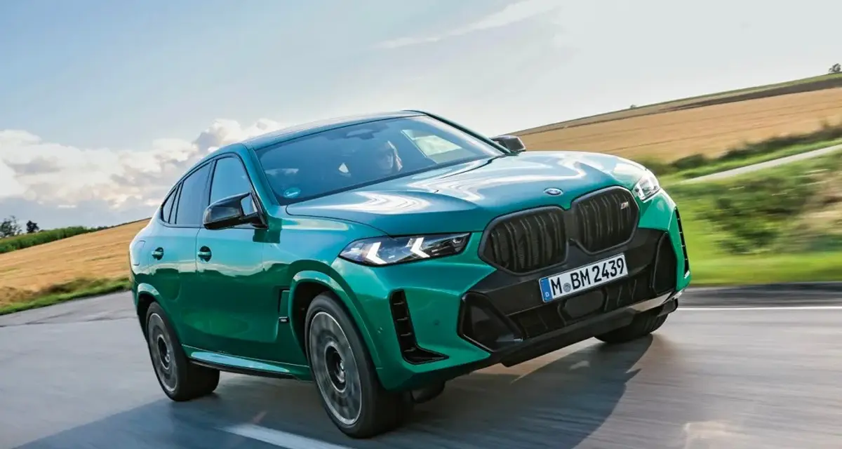Zielony suv coupe pędzi po drodze, otoczony polami i błękitnym niebem.