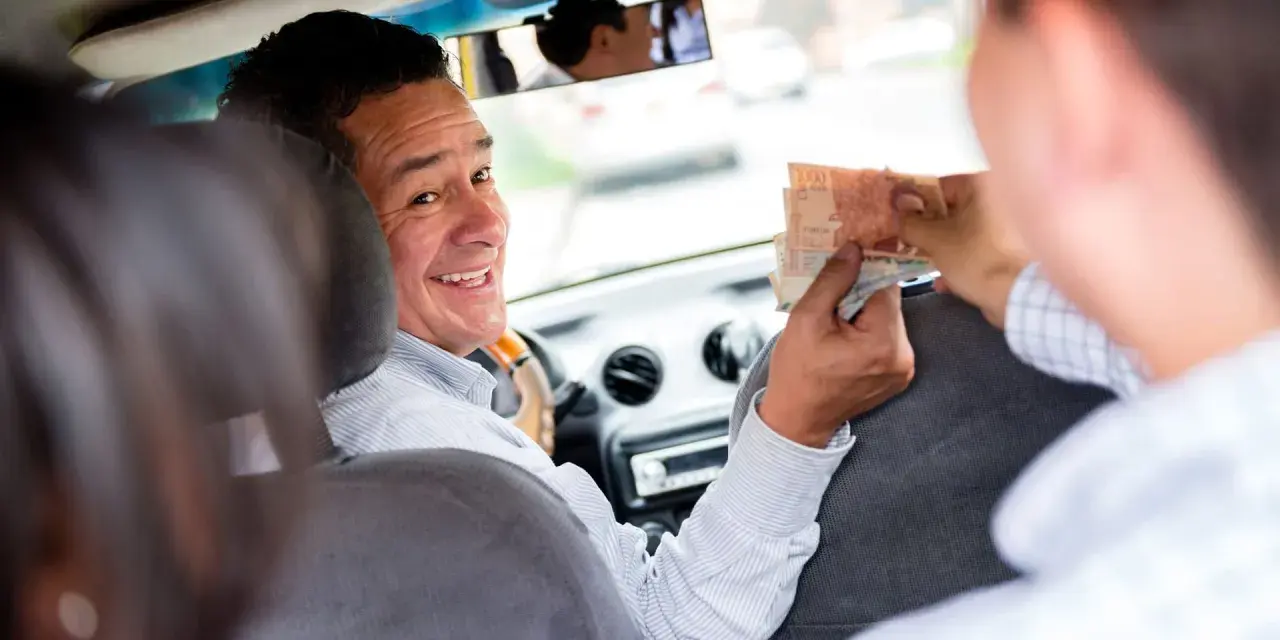 Ein Taxifahrer lächelt und nimmt Geld entgegen, ein Zeichen für ein gutes Taxi Trinkgeld.