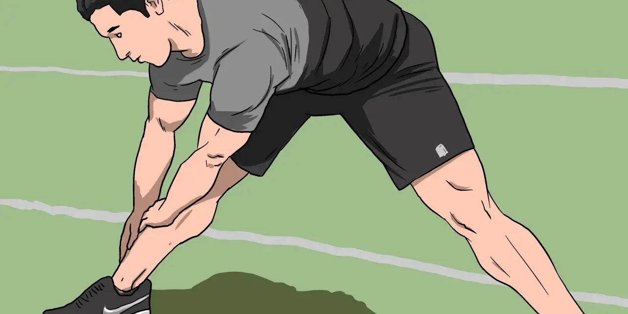 Man stretching his legs on a green indoor track, preparing for an intense indoor sprint workout.