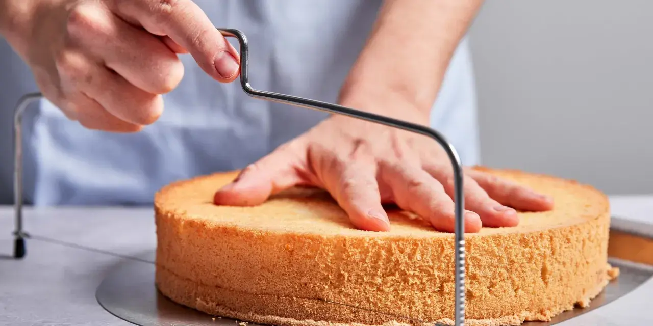 Hände schneiden mit einem Tortenbodenschneider einen Biskuitboden für ein einfaches Cassata Rezept.