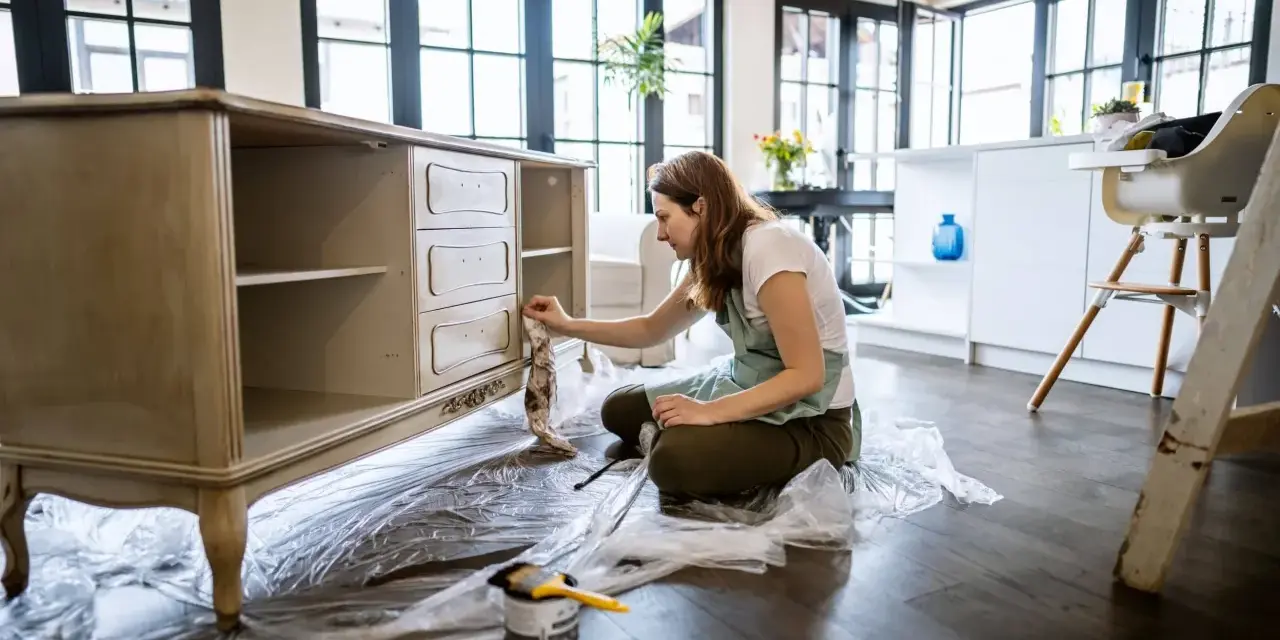 Mujer lijando muebles de madera antiguos para restaurarlos.