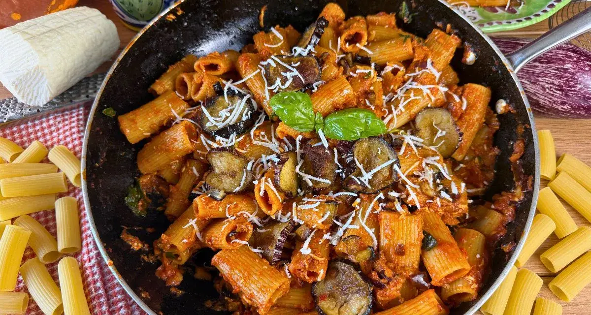 Rigatoni ricchi di melanzane fritte e pomodoro, conditi con ricotta salata grattugiata e basilico fresco. Un piatto di pasta alla norma invitante.