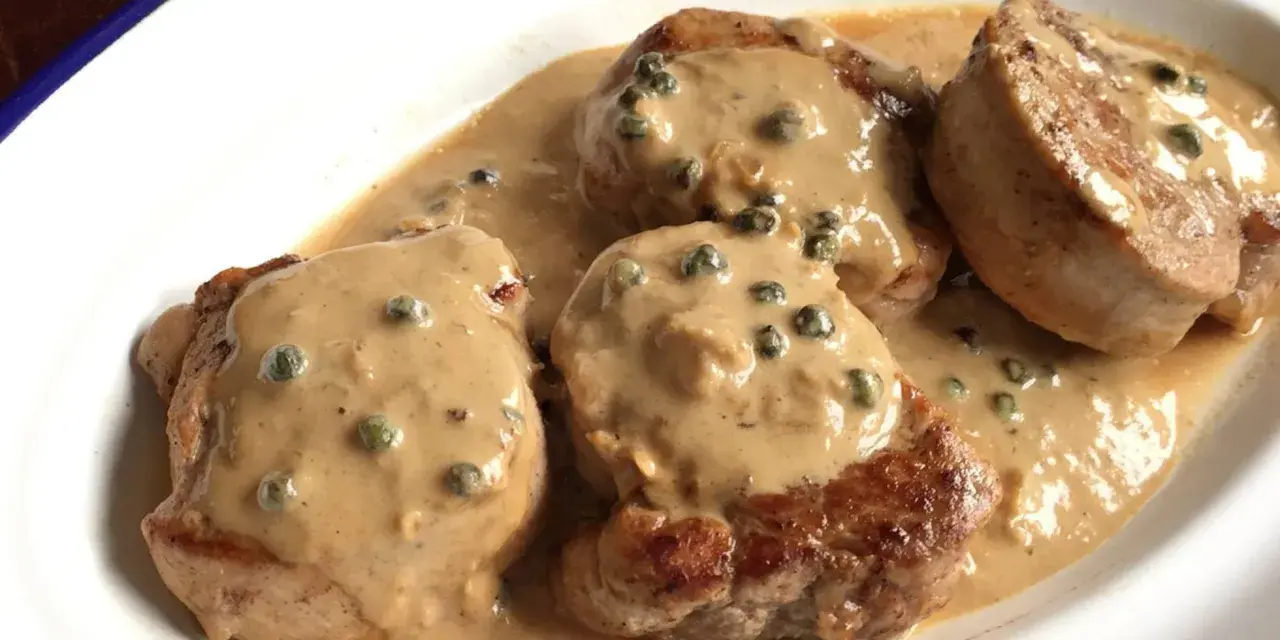 Cuatro medallones de solomillo a la pimienta en una cremosa salsa con granos de pimienta verde.