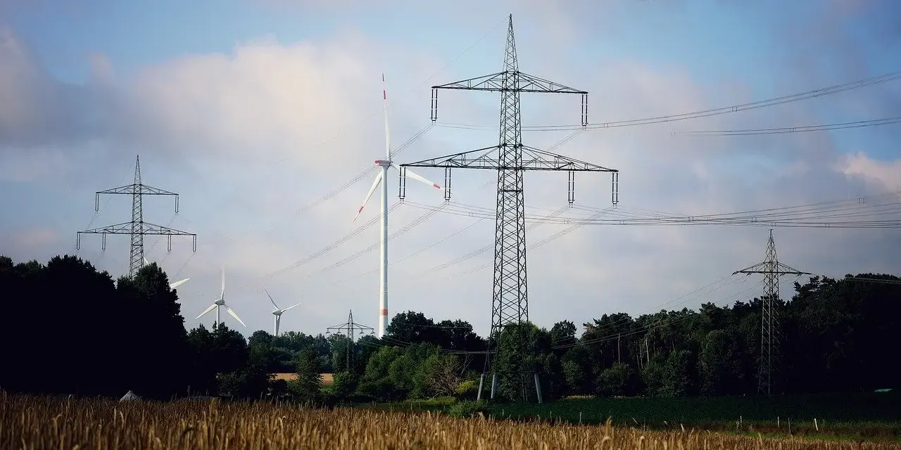 Wiatraki i linie energetyczne na tle nieba. OZE w Polsce to przyszłość, która już dziś zasila nasze domy.