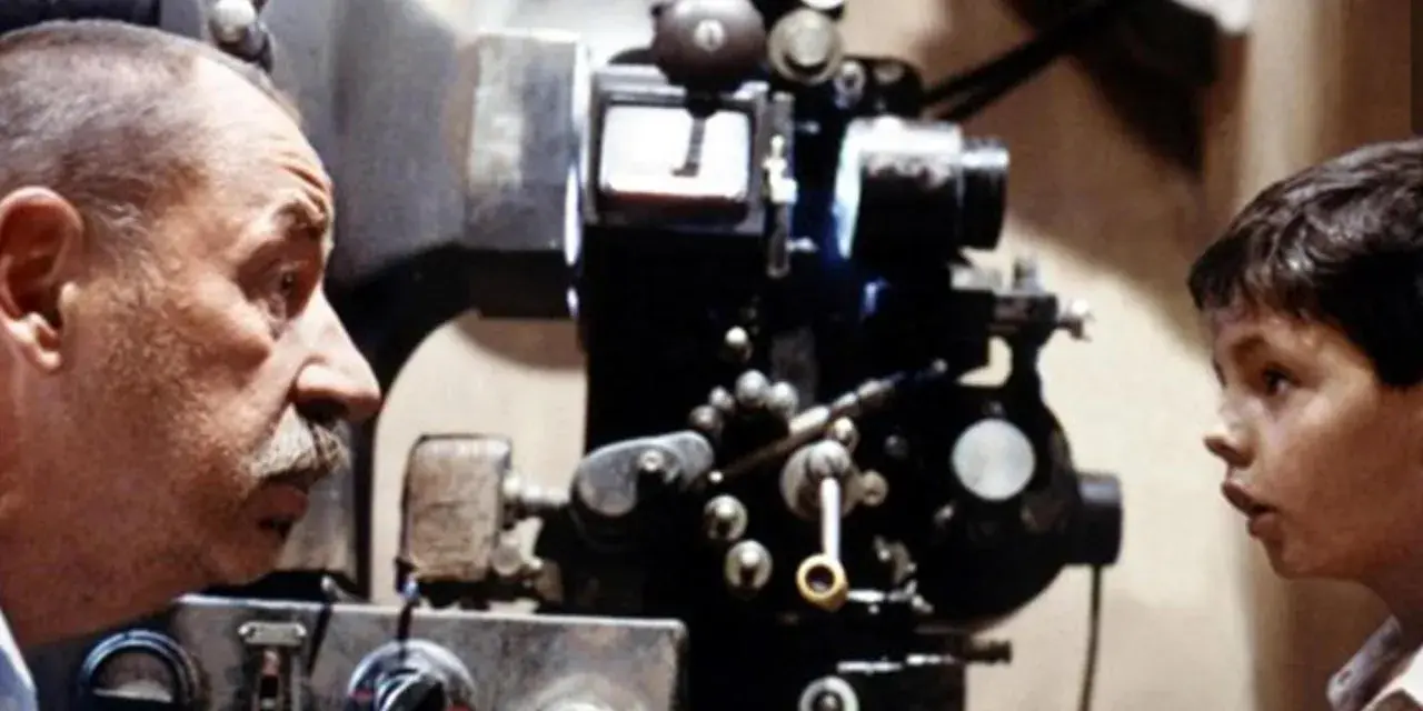 Un uomo e un bambino osservano affascinati una vecchia cinepresa, un'immagine che evoca le magiche tecniche cinematografiche.