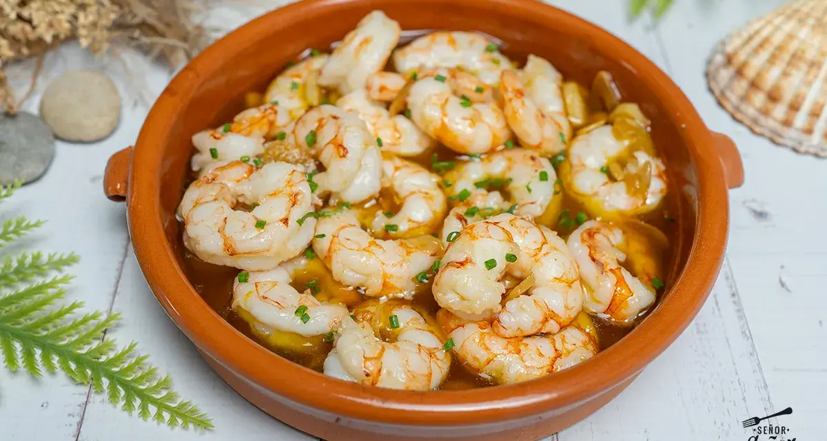 Gambas al ajillo burbujeantes en cazuela de barro, con perejil picado y un toque de aceite de oliva. ¡Un clásico irresistible!