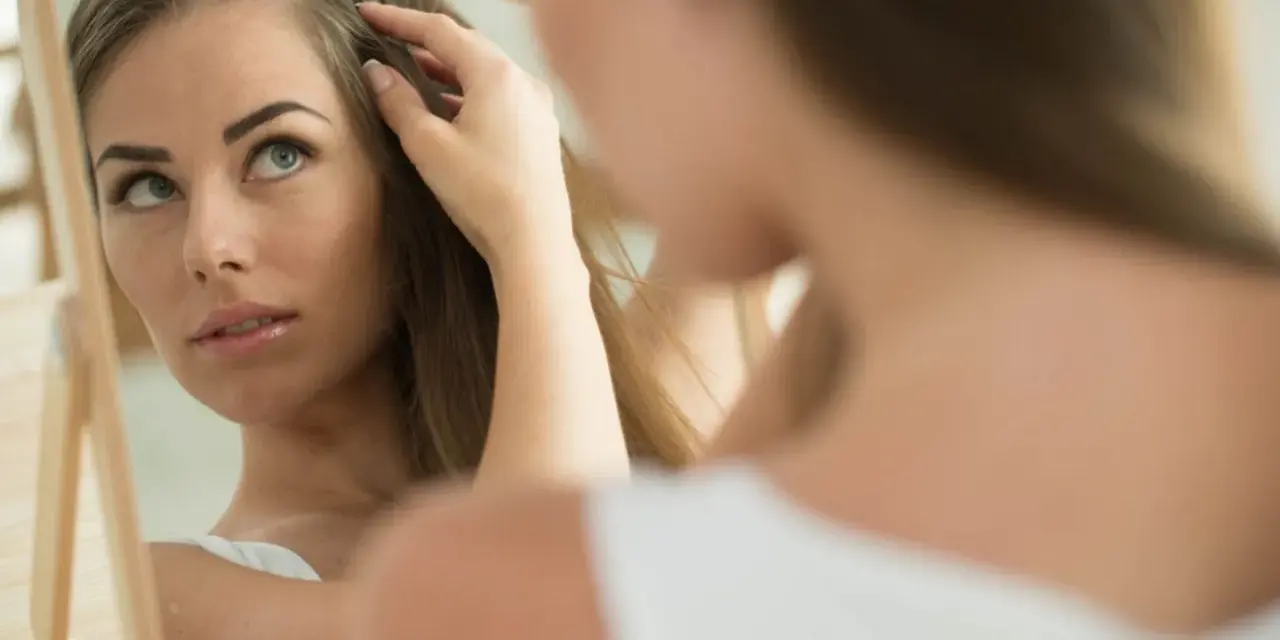 Besorgte Frau prüft im Spiegel ihr Haar, möglicherweise wegen Haarausfall in der Schwangerschaft.