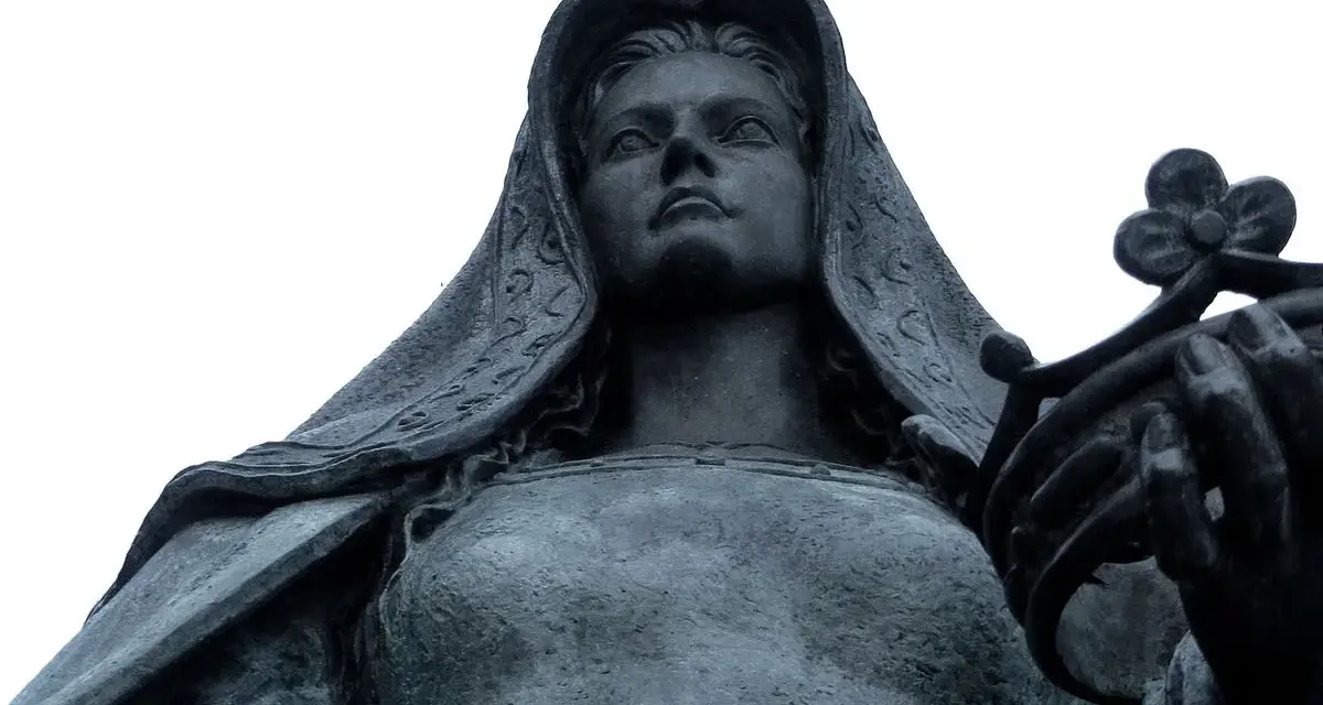 Statue de Jeanne la Folle, voilée, tenant une couronne de fleurs. Son regard est tourné vers le ciel.