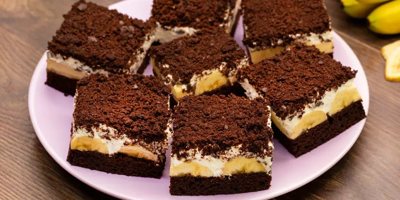 Saftiger Maulwurfkuchen vom Blech mit Bananen und Schokostreuseln auf einem rosa Teller.