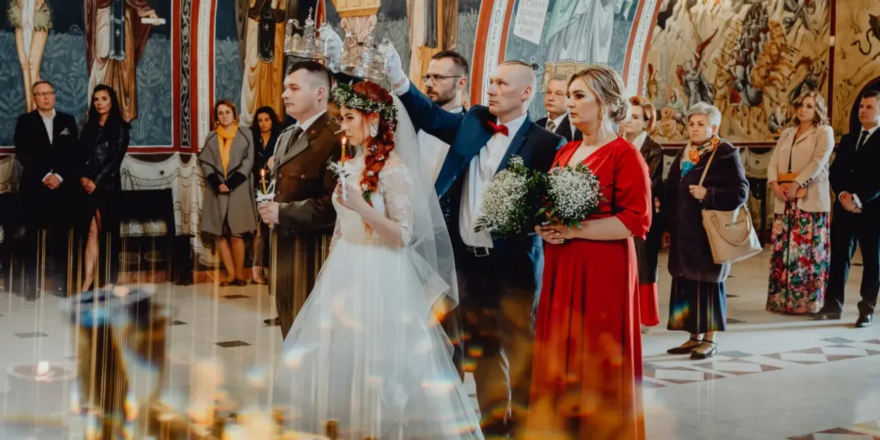 Para młoda podczas ceremonii ślubu prawosławnego. Pan młody w mundurze, panna młoda w bieli. Nad nimi trzymane są korony.