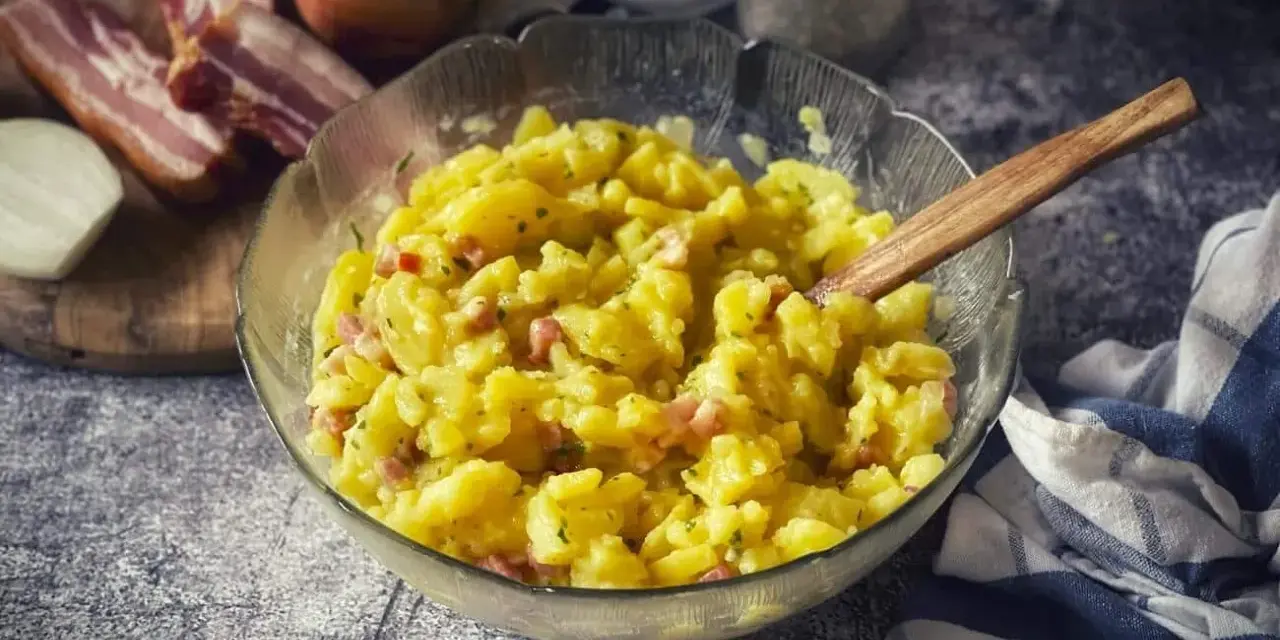 Ein Schüssel voller warmer Kartoffelsalat mit Speck und Zwiebeln, bereit zum Servieren.