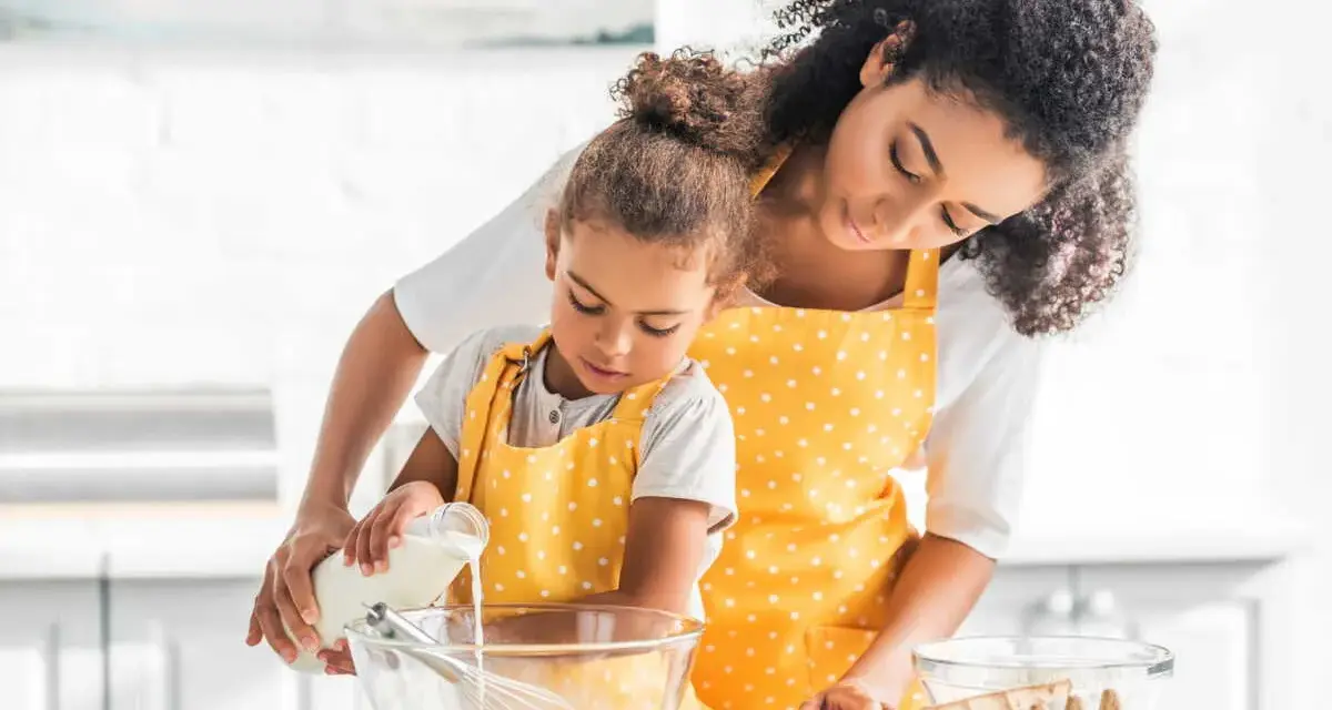 Une mère et sa fille préparent une recette, la petite verse du lait ribot dans un bol.