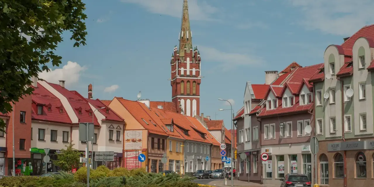 Kętrzyn atrakcje: malowniczy rynek z charakterystyczną wieżą kościelną, kolorowe kamienice i zielone skwery.