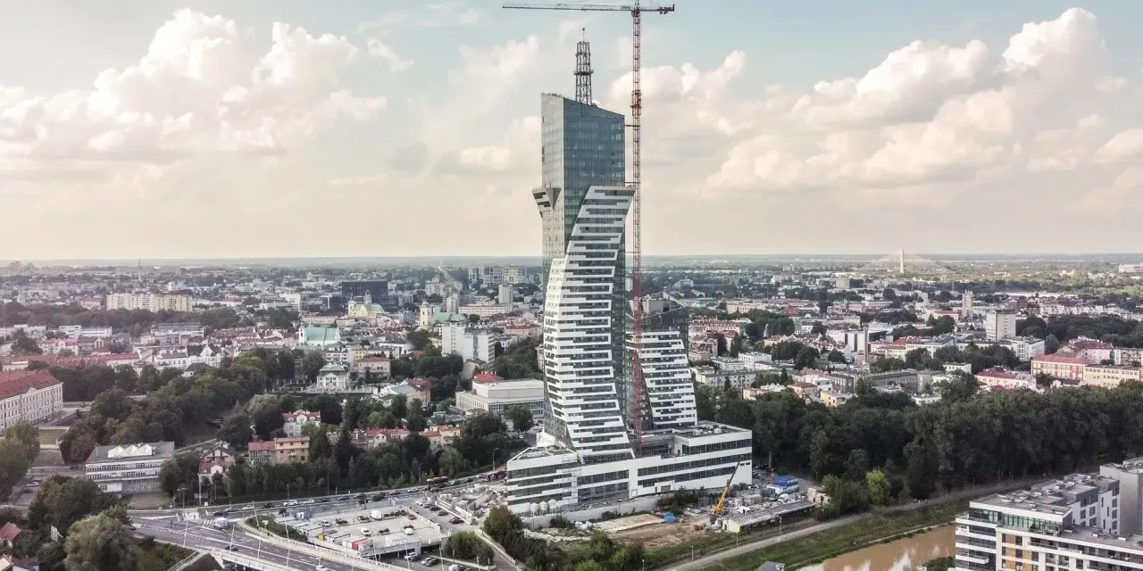 Wielka, kręcona wieża góruje nad miastem. To najwyższy budynek mieszkalny w Polsce, wciąż w budowie, z dźwigiem na szczycie.