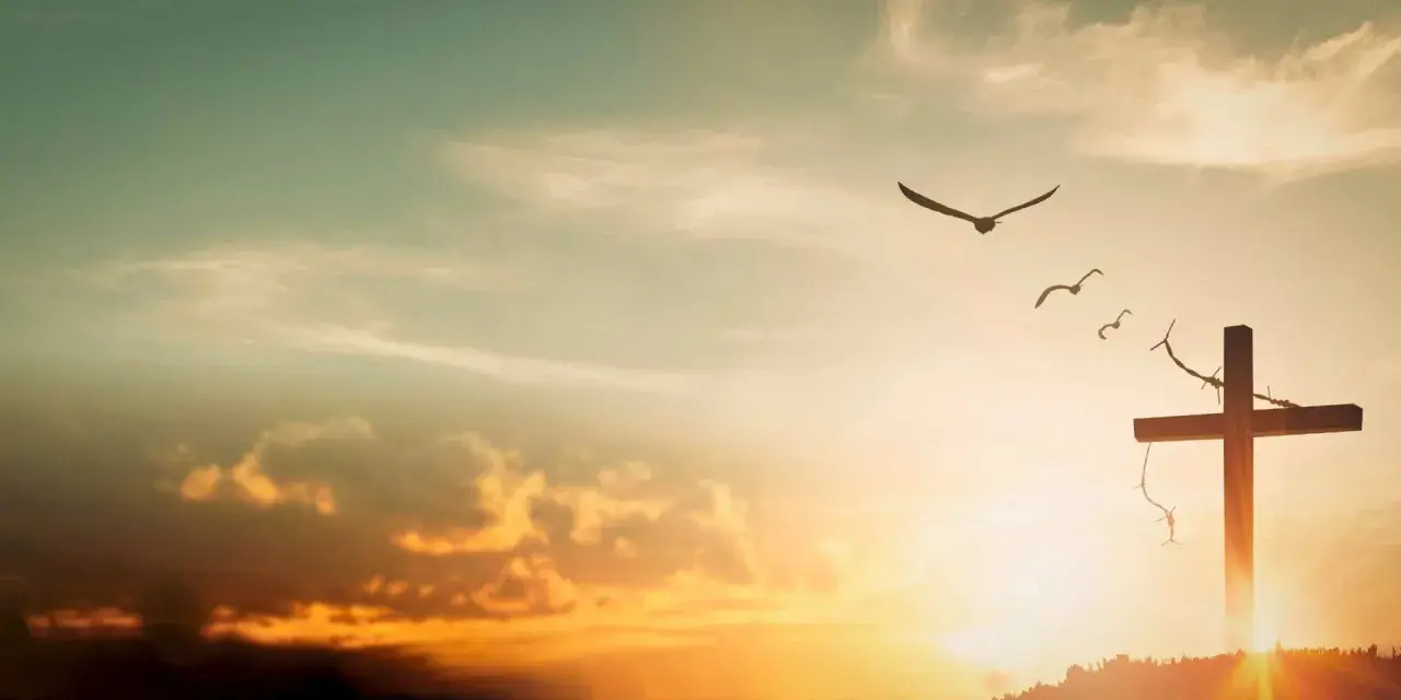 A cross on a hill, adorned with thorns, stands against a sunset sky. Birds fly overhead, symbolizing the feast of the exaltation of the holy cross.