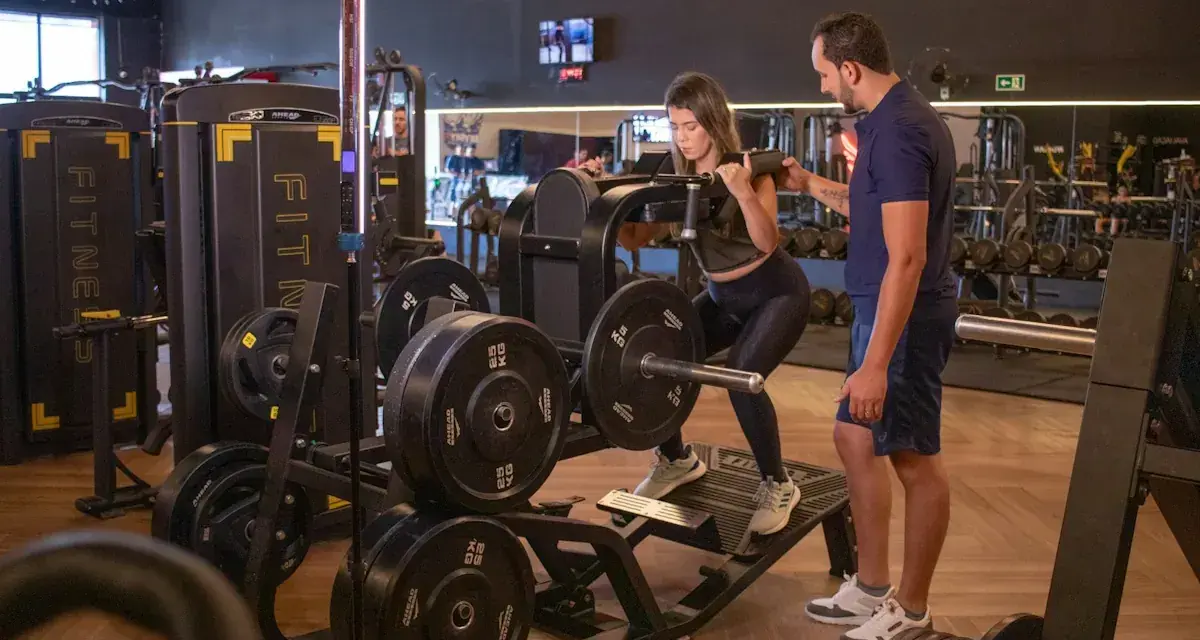 Kvinna utför benpress med instruktör som övervakar. En del av ett effektivt bro split-träningspass.