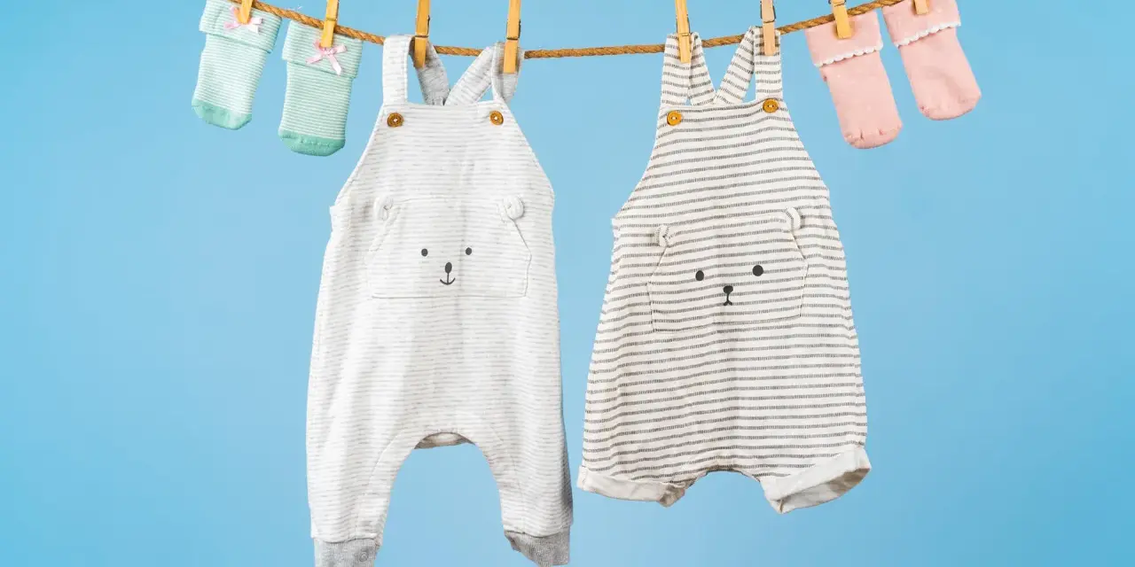 Ropa de bebé colgada para secar: dos peleles con caritas de oso y calcetines a juego. ¡El momento perfecto para saber cuando lavar la ropa del bebé!