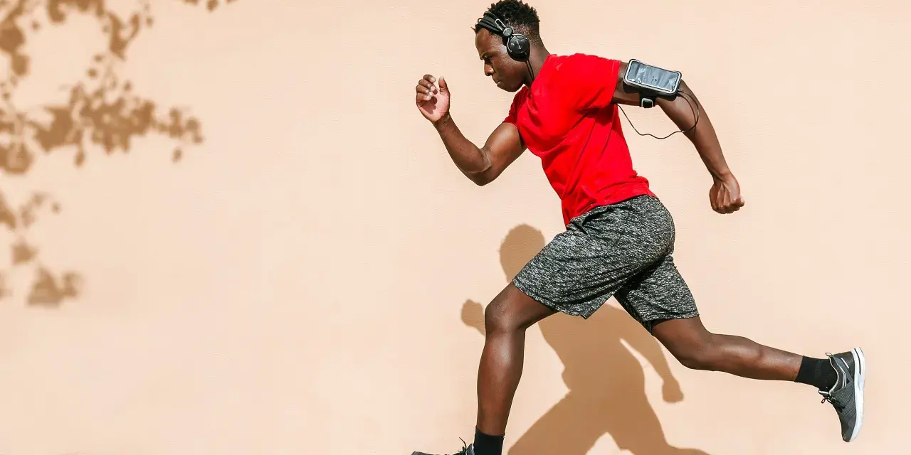 Hombre corre con audífonos y brazalete para celular. ¡Correr quema grasa y te da energía!