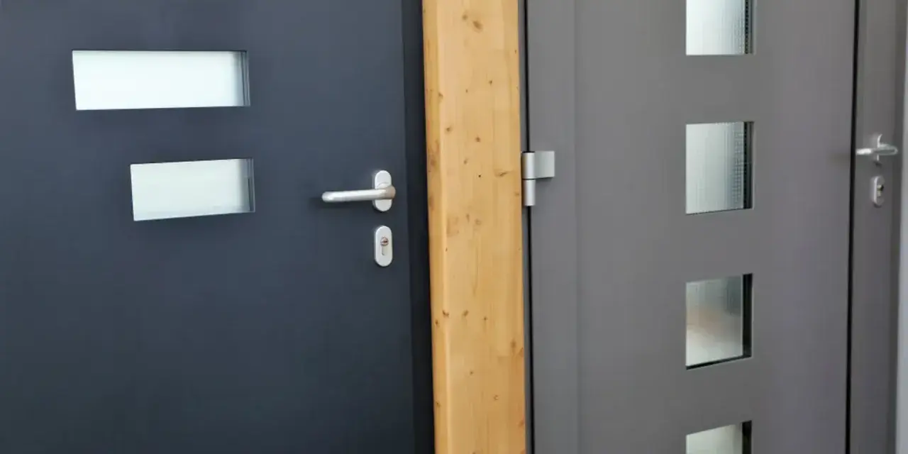 Dwie nowoczesne drzwi wejściowe, jedna ciemnoszara z prostokątnymi przeszkleniami, druga szara z kwadratowymi. Dowiedz się, jak uszczelnić drzwi wejściowe.