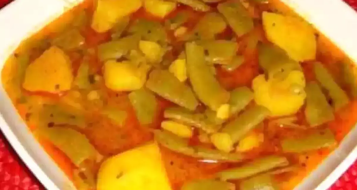 Un plato humeante de judías verdes con patatas, cocinado en una sabrosa salsa rojiza.