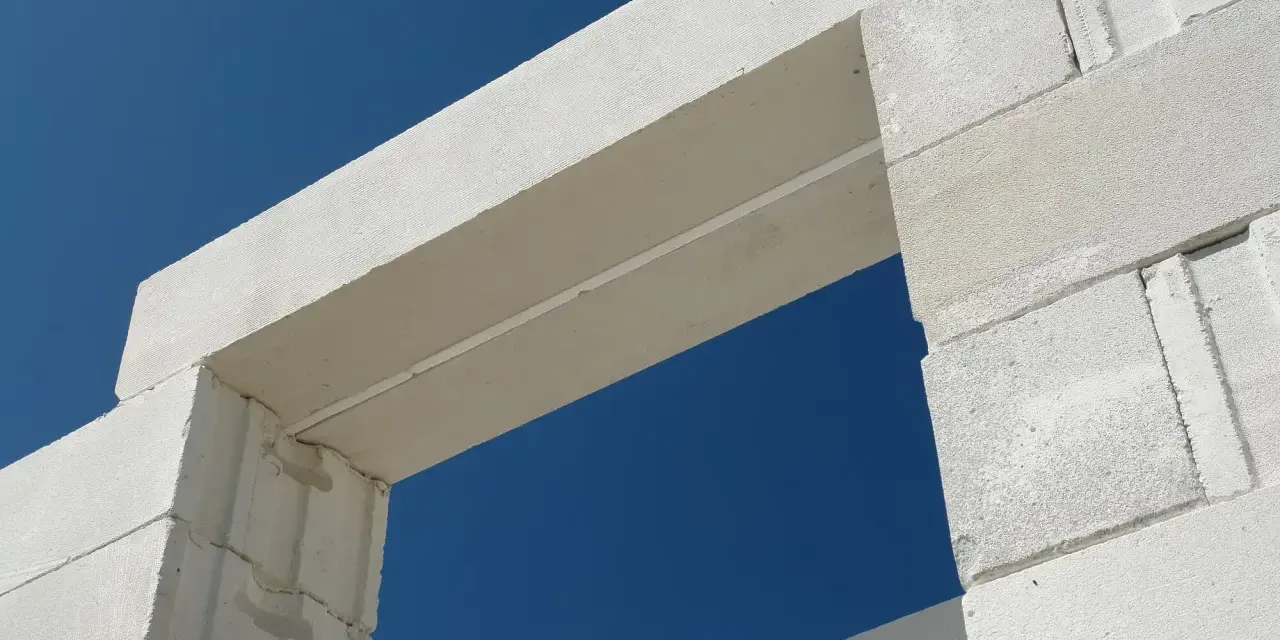 Białe nadproże nad drzwiami 90, wykonane z bloczków z betonu komórkowego, na tle błękitnego nieba.