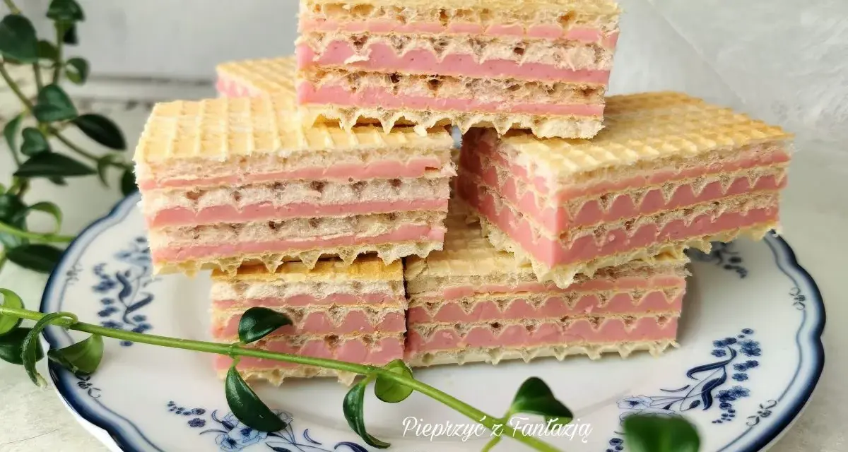 Piękne wafle z mlekiem w proszku, ułożone na talerzyku z niebieskimi wzorami, ozdobione zielonymi listkami.
