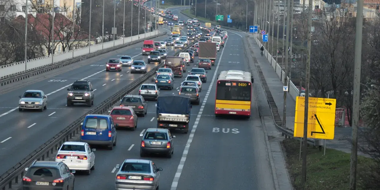 Autobus jedzie pasem dla autobusów. Wokół ruch samochodowy.