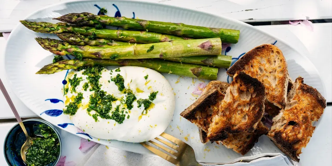Burrata med sparris och rostat bröd, toppad med en fräsch gremolata. Perfekt för ett lätt sommarmål.