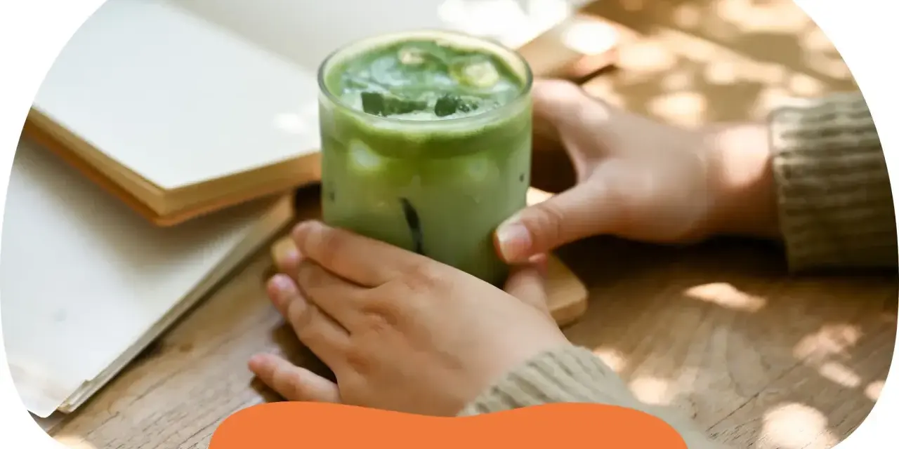Zielony napój matcha z lodem w szklance, obok otwartej książki. Zastanawiasz się, ile kalorii ma matcha?