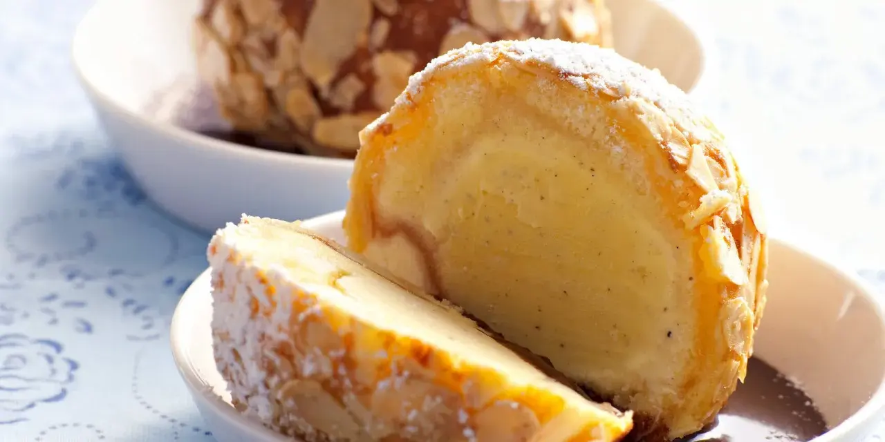 Zwei Portionen gebratenes Eis, umhüllt von Mandelsplittern und mit Puderzucker bestäubt, serviert in weißen Schalen.