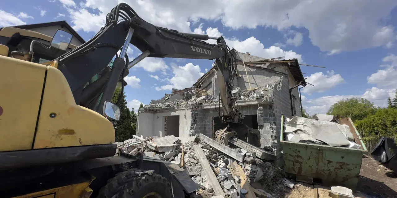 Koparka Volvo niszczy budynek. Trwa rozbiórka budynku, cena za m2 jest kluczowa przy planowaniu prac.