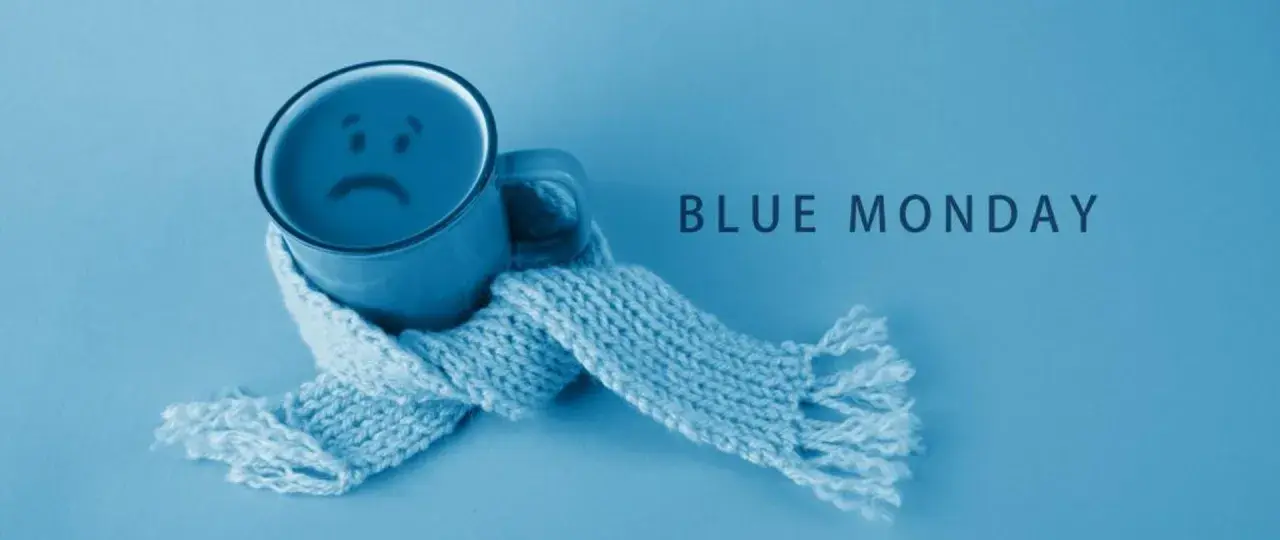 Smutny kubek z uśmiechem, otulony szalikiem, symbolizuje blue monday.