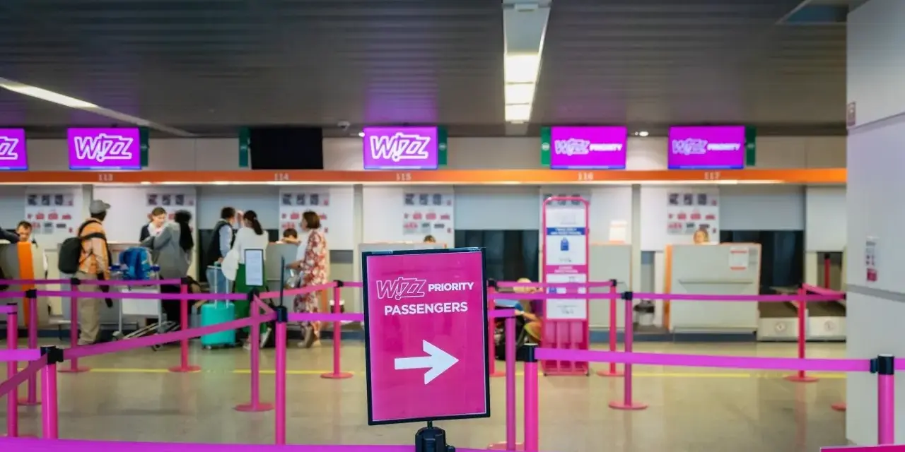 Kasa Wizz Air, gdzie pasażerowie dokonują self check-in. Różowe taśmy wyznaczają kolejkę do stanowisk odprawy.