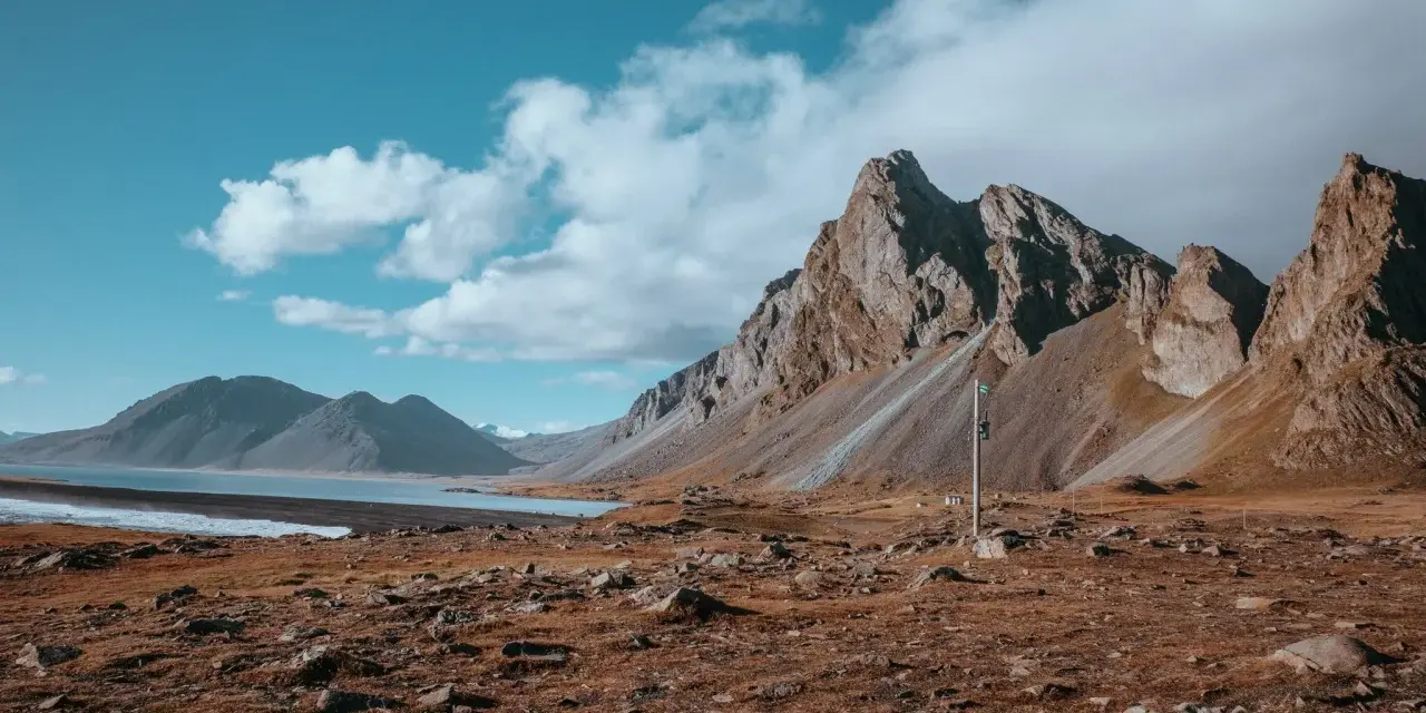 Krajobraz Islandii z górami i jeziorem. Wietrzna reykjavik pogoda z chmurami na niebie.