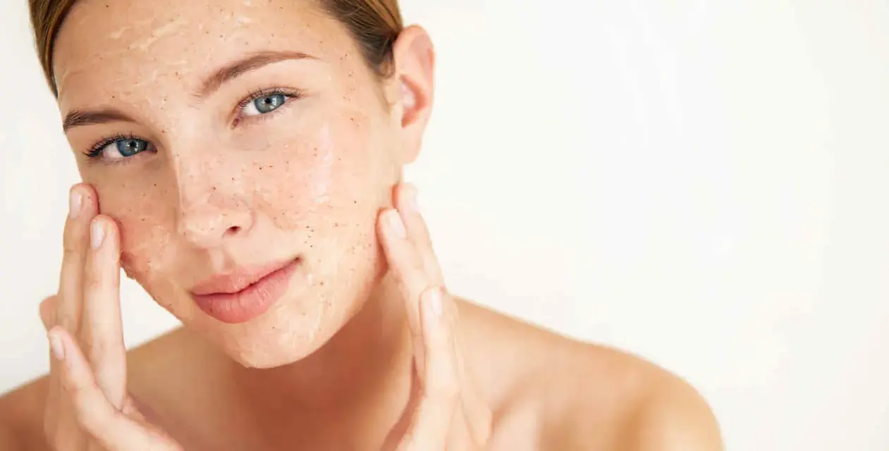 Mujer aplicándose una mascarilla exfoliante con vinagre de manzana para la cara. Sus dedos masajean suavemente el producto.