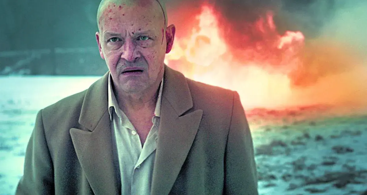 Jan Frycz w dramatycznej scenie, jak z najlepszych filmów i seriali. W tle płomienie, na głowie ślady walki.