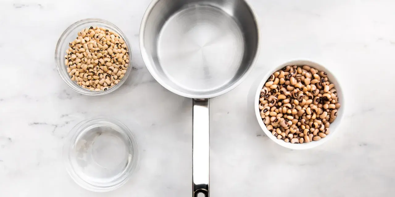 Vorbereitung zum Bohne kochen: zwei Schüsseln mit Schwarzaugenbohnen, ein Topf und eine Schüssel Wasser auf Marmoruntergrund.