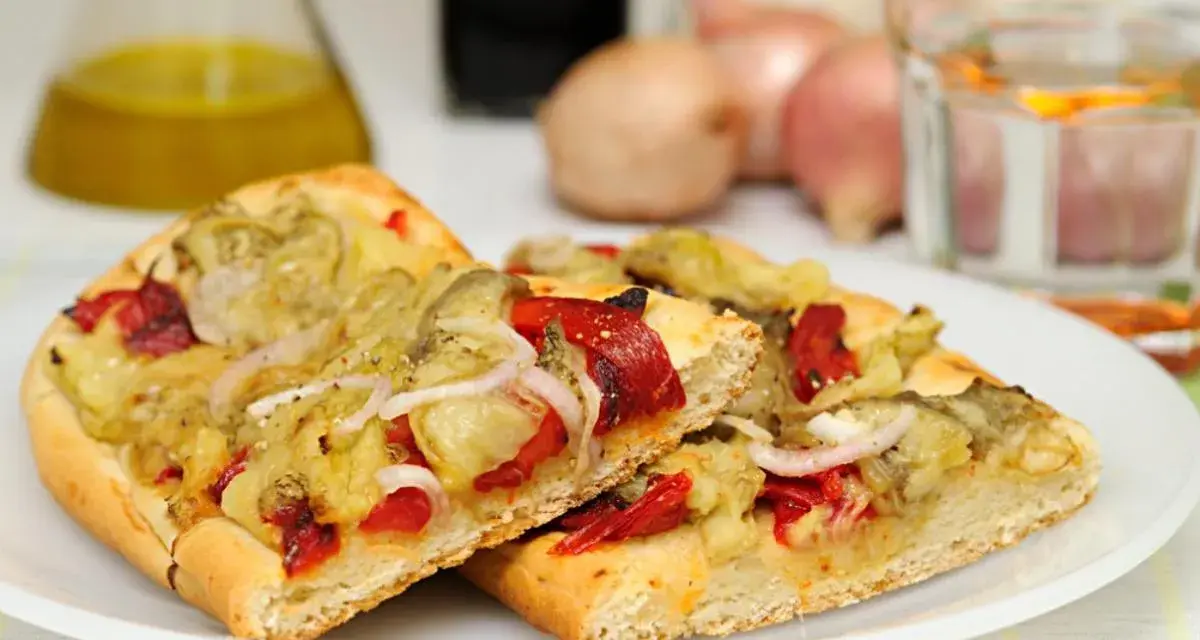 Dos porciones de coca de recapte con verduras asadas, pimientos rojos y cebolla.